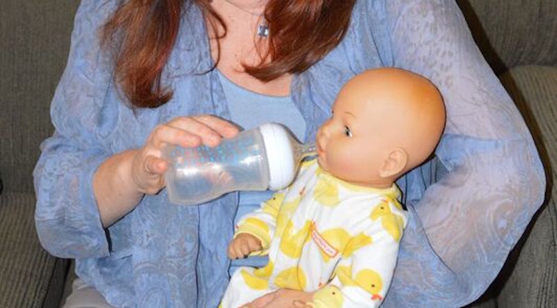 Barbara Robertson pacing the bottle pretend baby on couch